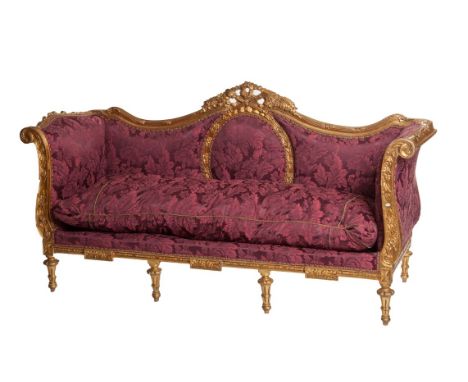 A LARGE GILT SETTEE, with trophy and ribbon crest, above an oval padded panel, and two conforming side panels, flanked to eit