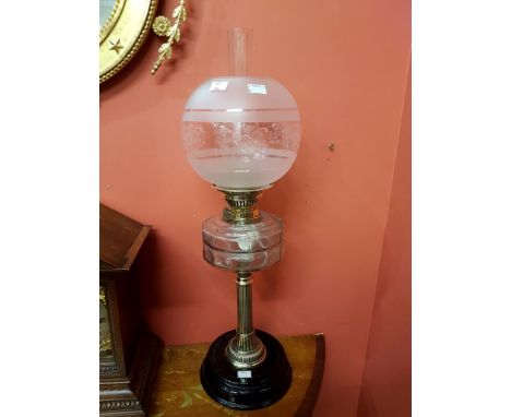 A BRASS AND GLASS OIL LAMP, with glass see-through reservoir, frosted and clear glass bulbous shade, raised on a reeded brass