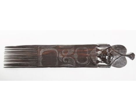 AN AFRICAN CARVED EBONY CEREMONIAL COMB, with thirteen extra long tapering teeth, the top surmounted with female mask, with h