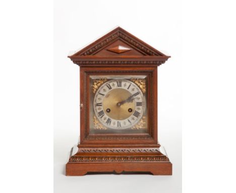 AN OAK CASED BRACKET CLOCK, with square brass dial and Roman numerals, the case of architectural design, with a arched pedime