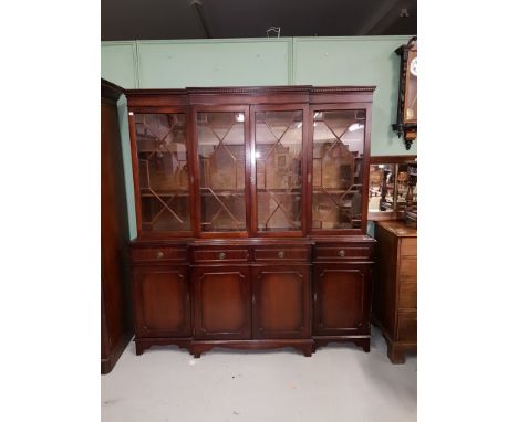 A SMALL GEORGIAN STYLE MAHOGANY BREAKFRONT BOOKCASE, O.R.M., the dentil moulded cornice above four astragal glazed doors, on 