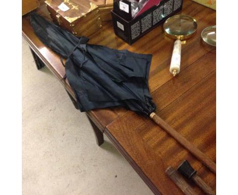 A vintage umbrella. Early 20th century with stitched leather handle, and brass finial & collar.