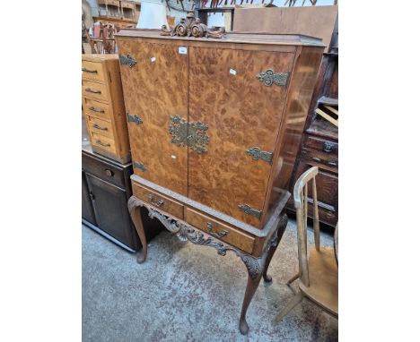 A mid 20th century Queen Anne style burr walnut cocktail/drinks cabinet with carved frieze and mirrored interior.