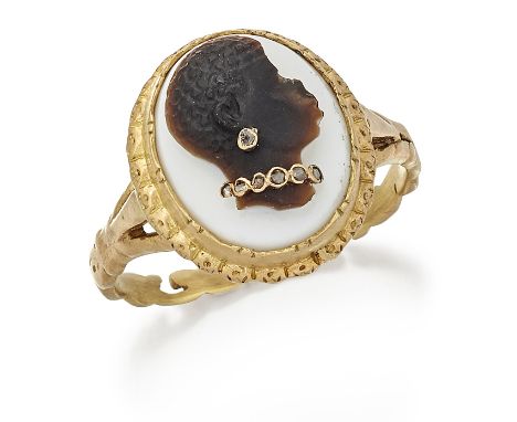 A CARVED HARDSTONE CAMEO HABILLÉS RING, depicting the bust of a Blackamoor, wearing a diamond earring and necklace, within a 