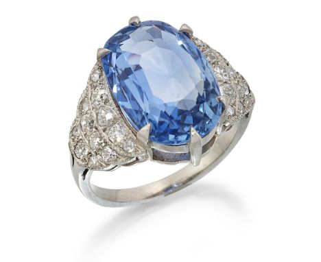 AN ART DECO STYLE CEYLON SAPPHIRE AND DIAMOND RING, an oval-cut sapphire in a claw setting, to diamond set stepped shoulders,