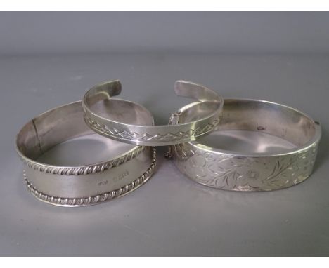 THREE SILVER BANGLES to include a 1906 Edwardian with rope edging and a 1975 hinged bangle, 2.2 troy ozs, 72grms total