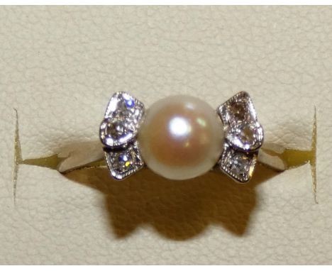 An 18ct white gold pearl and diamond ring, peg set with a cultured bead of 6mm, single cut diamond set shoulders, size N.