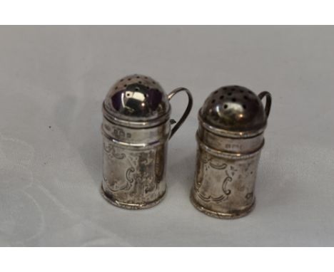 A pair of Edwardian silver pepperettes having domed lids, loop handles and plain cartouches, Birmingham 1906, C Brooks Ltd
We