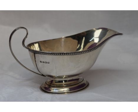 A silver sauce boat having gadrooned rim, loop handle and pedestal foot, Birmingham William Neale &amp; Son Ltd
Weight Approx
