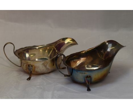 A pair of silver sauce boats of plain form having shaped rims, loop handles and trefoil paw feet, Sheffield 1932/33, Viners L