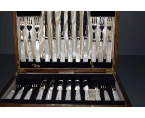 An oak canteen of 12 place setting of silver plated fruit knives and forks having mother of pearl handles