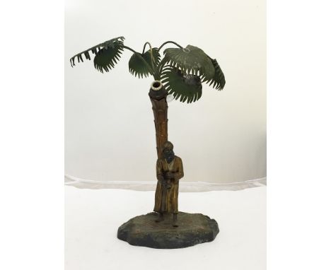 An Austrian cold painted spelter lamp of an Arab standing on a rug under a palm tree, marked to the base "Made in Austria AP"