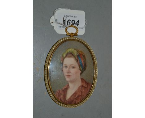 Early 20th Century watercolour, portrait miniature of a lady wearing a colourful head scarf and brown dress, in a gilt metal 