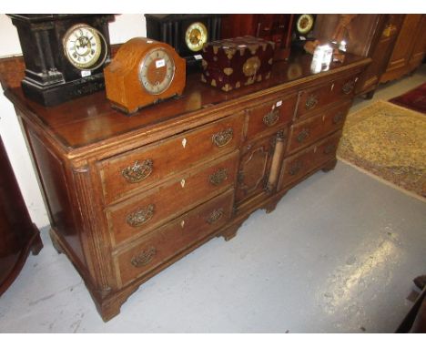 George III oak and mahogany crossbanded dresser base, the moulded top above an arrangement of seven drawers with brass handle