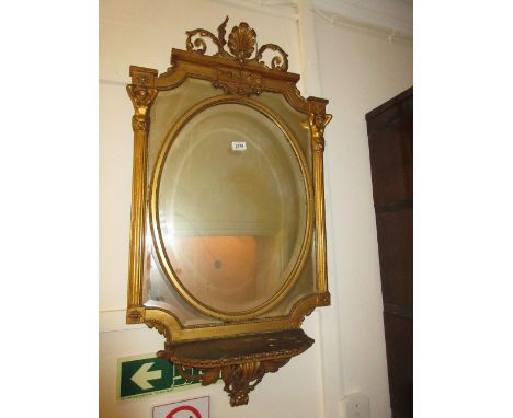 19th Century gilded composition wall mirror with a shell surmount, oval bevelled plate above a shelf (at fault)