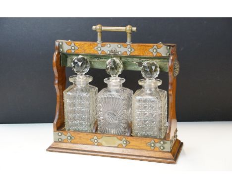 Early 20th Century oak tantalus housing three cut glass whisky decanters with lock to handle. Measures 36 x 36cm. 