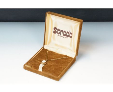 A 9ct gold white opal pendant on 9ct gold chain link necklace within display case. 
