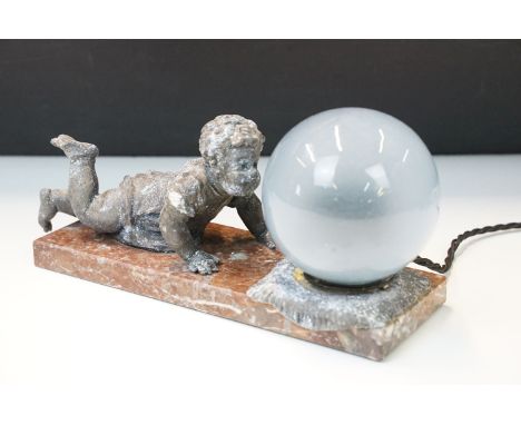 Marble based table lamp with cast spelter cherub beside glass shade. Measures 25cm wide. 