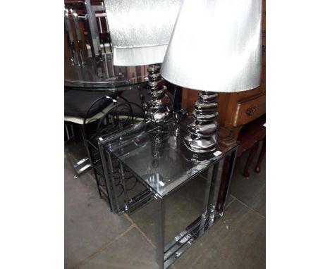 A chrome and glass nest of tables, two modern table lamps, a metal wine rack and a spare lamp shade. 