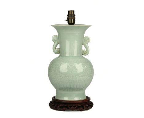 A Chinese celadon glazed twin handled vase probably 19th century, of baluster form with flared neck and everted rim, on a fla