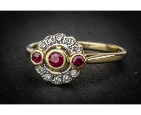 A 14ct yellow gold, ruby and diamond cluster ring the three graduated round cut rubies within scalloped borders of ten brilli
