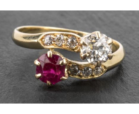 An 18ct yellow gold, ruby and diamond cross over ring set with a single 5mm. round cut ruby and a single approx. 0.5 carat ol