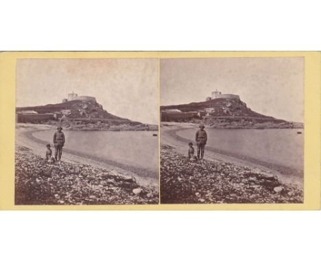 A Guernsey stereoview card depicting a Father and son onshore at L'Eree Bay during low tide, the elevated Fort Sausmarez can 