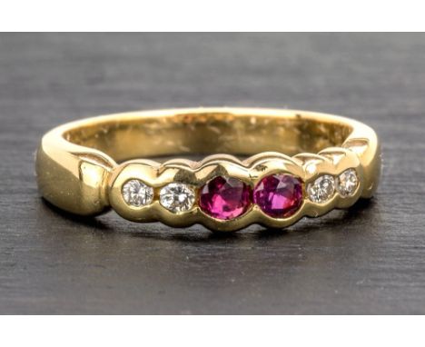 An 18ct yellow gold, ruby and diamond ring the scalloped band set with a pair of round cut rubies and four brilliant cut diam