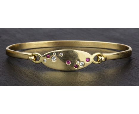 A 14ct yellow gold, ruby and diamond bangle the elliptical face inset with six graduated brilliant cut diamonds and four grad