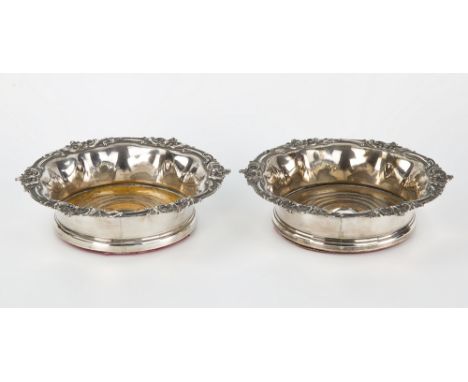 A pair of Sheffield plated wine coasters deep sides with everted rims bearing multiple cartouche detail, turned wooden bases 