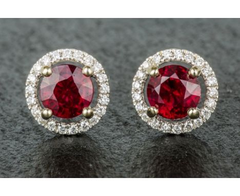 A pair of 18ct white gold, ruby and diamond cluster earrings the round cut rubies, total weight 2.07 carats, within a 'halo' 