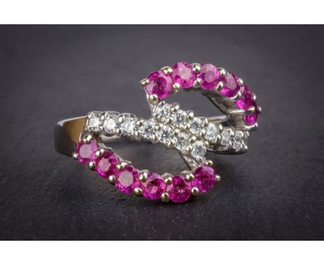 An 18ct white gold, ruby and diamond ring the split, pierced setting line-set with two rows of seven brilliant cut diamonds a