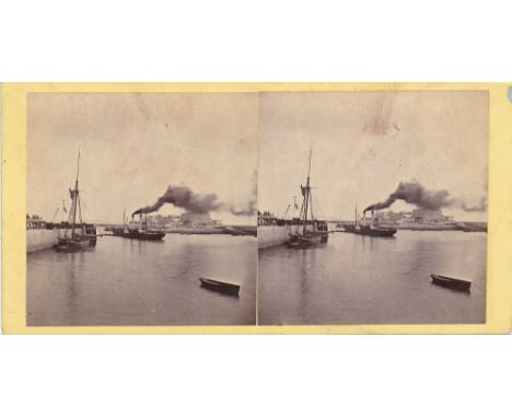 A Guernsey interest stereoview card showing St. Peter Port harbour with sailed vessel moored to populated quayside, while a s