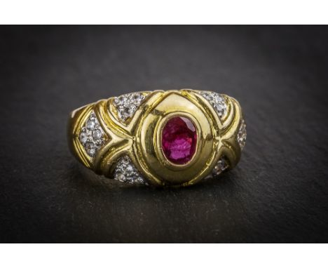 A 21ct yellow gold, ruby and diamond ring the collet set oval cut ruby within decorative shoulders set with groups of small r