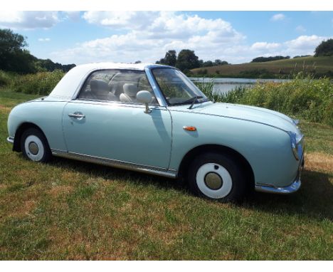 A 1991 Nissan Figaro automatic, registration number J521 UBM, light blue with white roof.  This retro car has a leather inter
