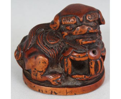A JAPANESE MEIJI PERIOD CARVED WOOD NETSUKE OF A SHI-SHI, unsigned, with a brocaded ball, 1.75in long & 1.6in high.