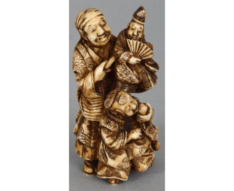 A JAPANESE MEIJI PERIOD IVORY OKIMONO OF A PUPPETEER & HIS SON, the standing man holding aloft a hand puppet, his son dancing