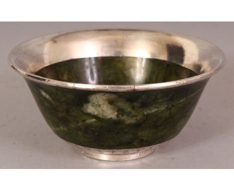 A SOUTH-EAST ASIAN SILVER FOIL MOUNTED JADE-LIKE BOWL, the striated predominantly green stone with lighter inclusions, 4in di