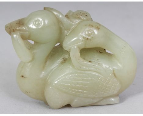 A CHINESE JADE-LIKE MODEL OF A PAIR OF DUCKS, bearing a lotus frond in their beaks, 1.8in long & 1.5in high.