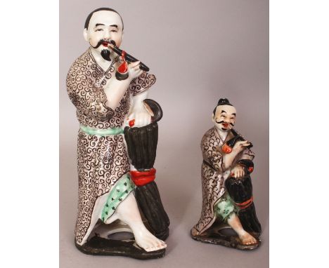 TWO 20TH CENTURY CHINESE ENAMEL DECORATED PORCELAIN FIGURES, each of a standing farmer leaning on a bale and smoking a pipe, 