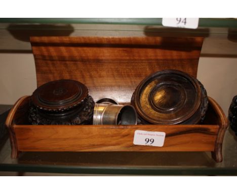 A carved hardwood trinket box containing two oriental hardwood stands; four serviette rings to include one silver; a small mo
