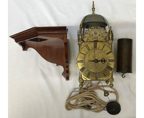 An old reproduction lantern clock with pulley, weight and wooden corner mounted shelf. A single pointer on a hand carved meta