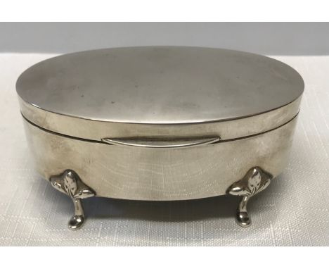 A hallmarked silver oval shaped trinket box on four pad feet with lined interior. Chester 1921. Gross weight including liner 