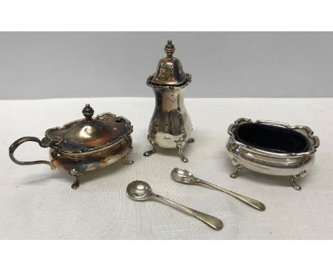 A hallmarked silver condiment set of three with two spoons and blue glass liners marked R and B Sheffield 1975. Weight withou