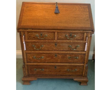 A good quality 20thC oak fall front bureau. Cross banding to fall front and drawers with brass swan necked handles and ogee b