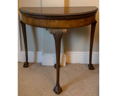A burr walnut demi lune fold over card table on cabriole legs with ball and claw feet and brown felt surface. 84cms x 42cms. 