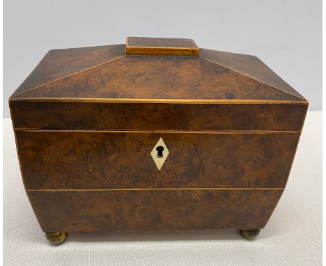 An early 19thC sarcophagus shaped tea caddy in burr yew with ivory escutcheons and ring handles to the side. Approx. 14cms h 