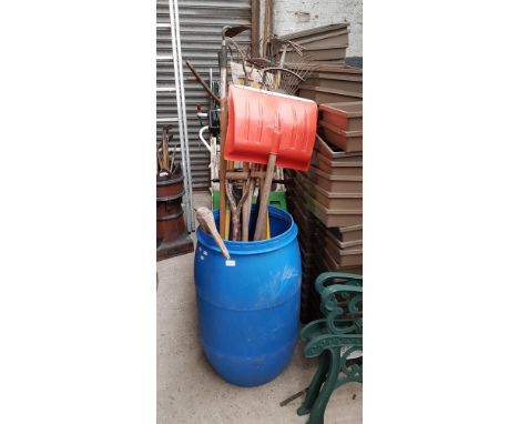 A Kawasaki petrol lawnmower and a blue barrel containing various garden tools. 