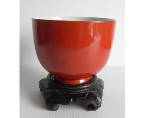 A fine red-glazed Chinese monochrome bowl on carved wooden stand with impressed seal mark to base, possibly Kangxi, 11 cm H x