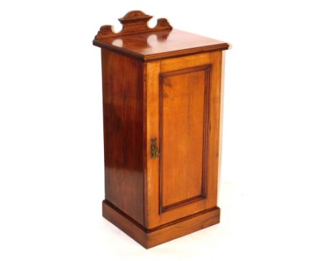 A Victorian walnut pot cupboard, with a carved back pediment, above a door enclosing a single shelf, raised on a plinth base,